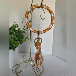 Orange and White Key Holder has Paw print design with a tassel and charm accent.